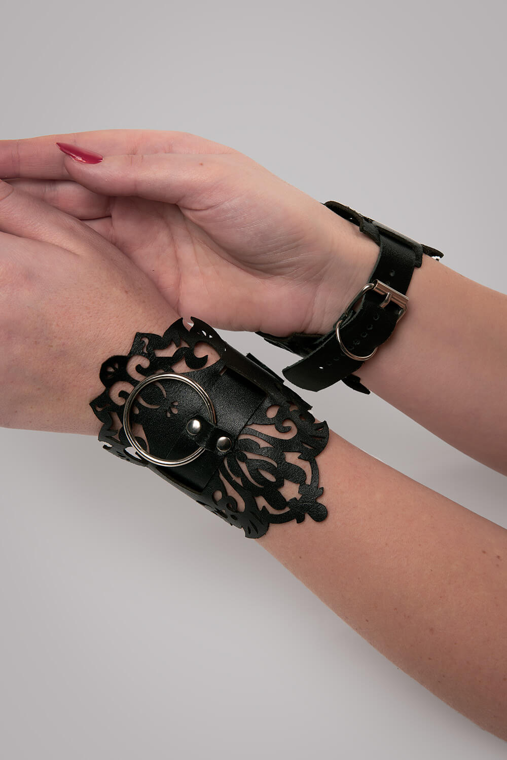 Leren handboeien lasercut Lucy zwart op handen